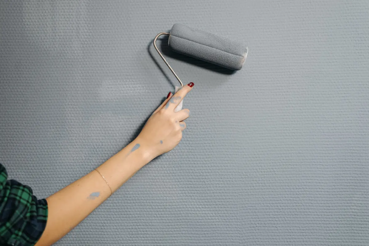 Paint roller applying gray paint to an interior wall