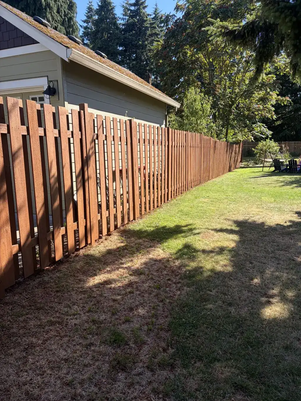 Stained wood privacy fence along a backyard